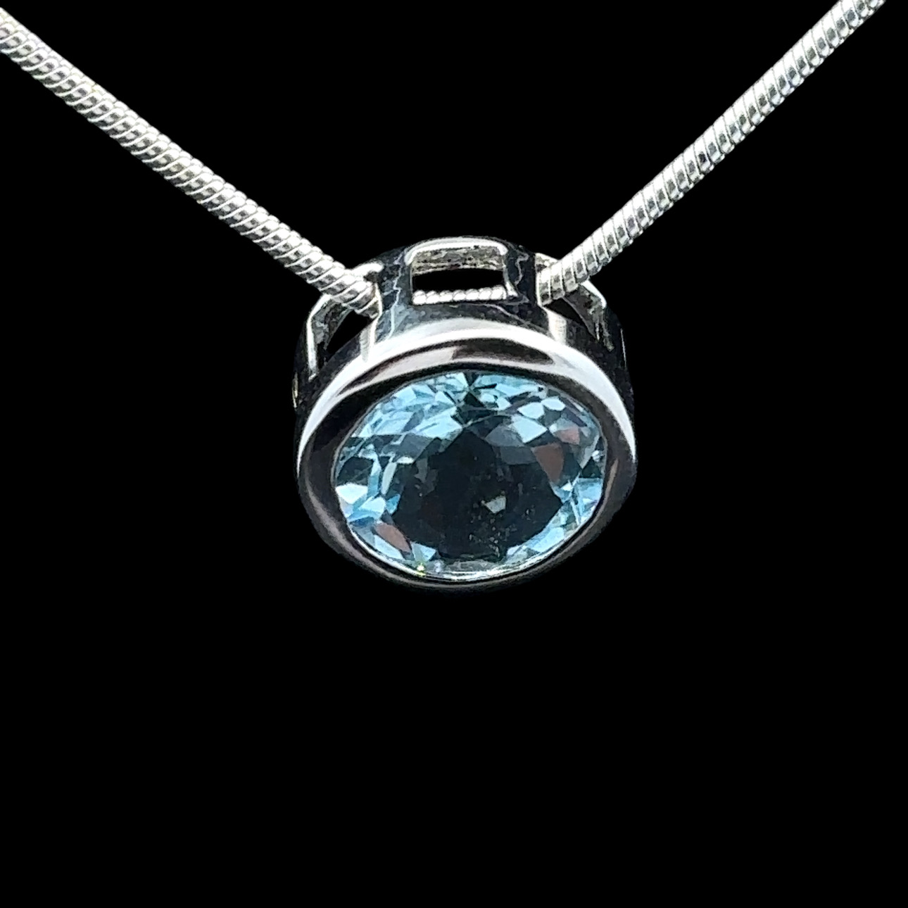 Round faceted blue topaz and rhodium-plated silver pendant